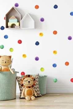 two stuffed animals sitting on top of baskets in front of a wall with multicolored polka dot decals