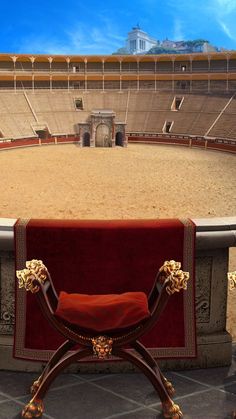 a red chair sitting on top of a stone floor in front of an empty arena