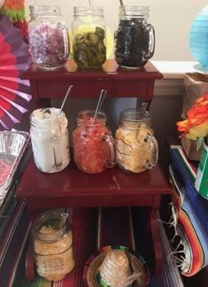 there are many jars and containers on the shelf with paper fans in the back ground