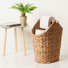 a basket with toilet paper and a potted plant