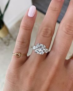 a woman's hand with two rings on it and a diamond ring in the middle