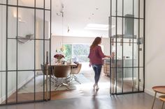 a woman is walking through an open glass door to the dining room and kitchen area