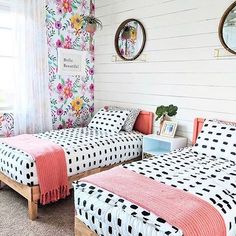 two beds in a room with floral wallpaper and mirrors on the walls above them