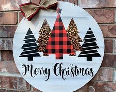 a merry christmas sign hanging on the side of a brick wall next to a red and black bow