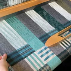 someone is working on a weaving machine with a wooden spoon next to the loom