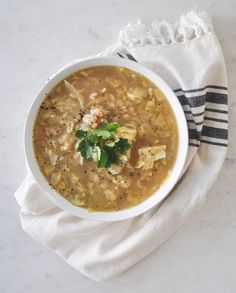 a white bowl filled with soup sitting on top of a table next to a towel