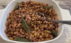 a white bowl filled with beans and cucumbers on top of a wooden table