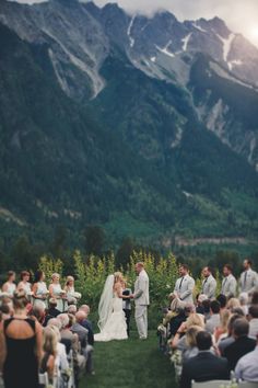 a bride and groom standing at the end of their wedding ceremony with mountains in the background