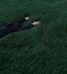 a person laying in the grass with their arms out