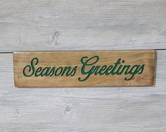 a wooden sign that says seasons greetings on the side of a white wood wall