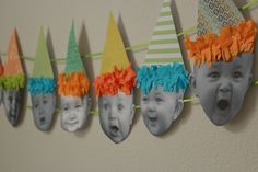 a group of children's hats hanging on a wall with their faces painted orange, green, and blue