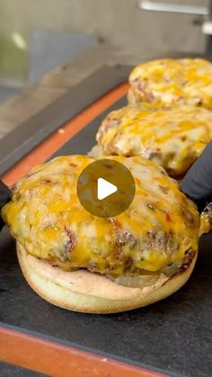 two hamburgers with cheese and other toppings are being prepared on a conveyor belt