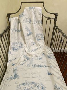 an unmade crib with a white and blue bed spread on top of it