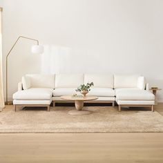 a white couch sitting on top of a wooden floor in a living room next to a lamp