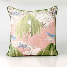 a pink and green pillow with an image of a tree on the front, clouds in the background