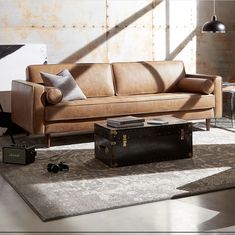 a leather couch sitting on top of a rug next to a table and suitcases