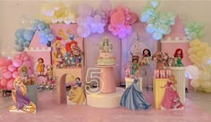 a birthday party with balloons and princess figurines on the floor in front of it