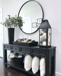 a black console table with white fluffy slippers on it and a round mirror above