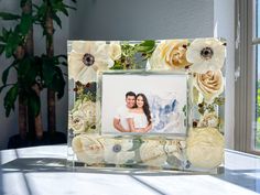 a photo frame with flowers on it sitting on a table