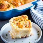 a piece of quiche sitting on a plate next to a casserole dish