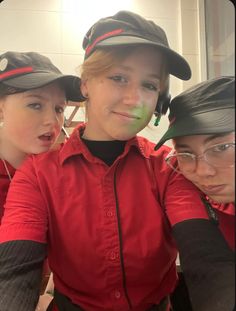 three girls in red shirts and black hats posing for the camera with their hands on their hips