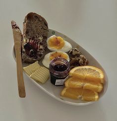 an assortment of food on a plate with bread, jam, and orange wedges