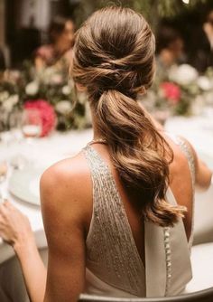 a woman sitting at a dinner table with her hair in a low pony tail braid