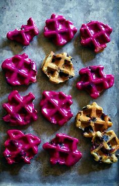 several waffles with purple icing are on a baking sheet, ready to be eaten