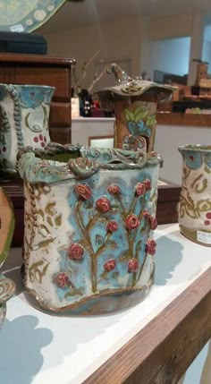 several vases and bowls on display in a room with other items behind them,