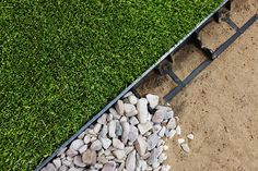 an aerial view of the grass and gravel in front of a metal rail with rocks on it