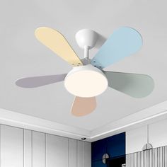 a white ceiling fan with multiple colored blades in a living room or dining room area