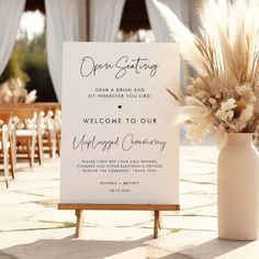 an open seating sign and vase with flowers on the ground in front of a wedding ceremony