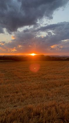 the sun is setting over an open field