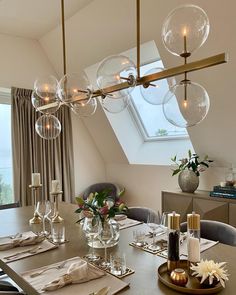 the dining room table is set with place settings for four people and there are glass globes hanging from the ceiling