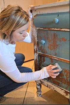 a woman is working on an old dresser