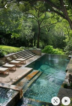 an outdoor swimming pool with lounge chairs next to it and trees in the back ground