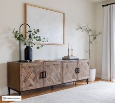 a wooden sideboard sitting on top of a hard wood floor next to a window