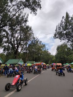 a group of people riding karts down a street with umbrellas on the sides