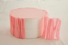 a roll of toilet paper sitting on top of a white tablecloth covered bed with pink ruffles