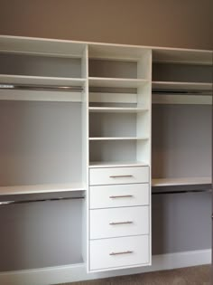 an empty walk in closet with white shelves and drawers