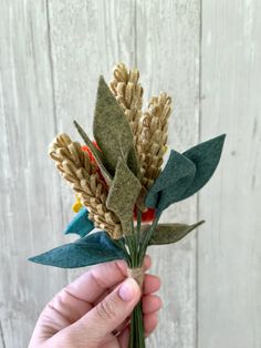 a person is holding some flowers in their hand and it looks like they are made out of felt