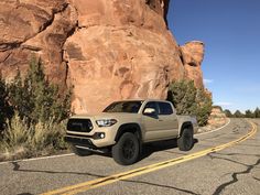 a toyota truck is parked in front of a large rock