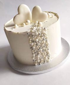 a white cake decorated with pearls and hearts