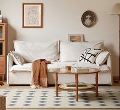 a living room with a white couch, coffee table and bookshelf in it