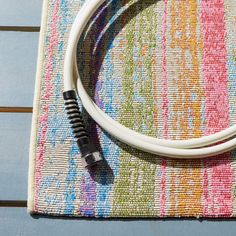 a close up of a white cord on a colorful cloth with a small black object in the middle