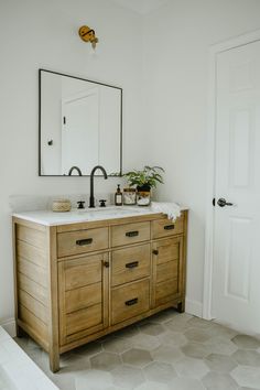 a bathroom vanity with two sinks and a large mirror above it, in front of a door