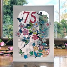 a greeting card with flowers and butterflies on the number 45, in front of a window