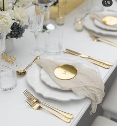 the table is set with gold and white plates, silverware, and napkins