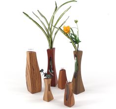 three wooden vases with flowers in them on a white surface, one is made out of wood