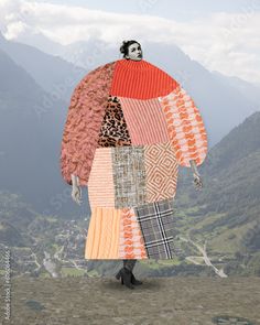 a woman is standing on top of a hill wearing a patchwork coat and black boots